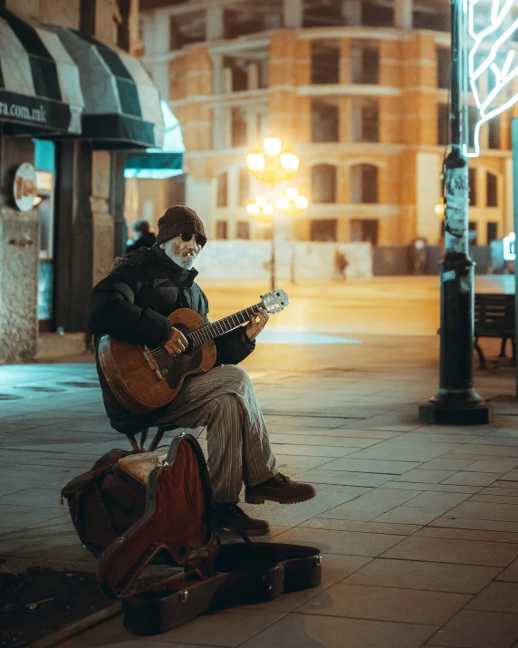 a man sits on a bench playing a guitar