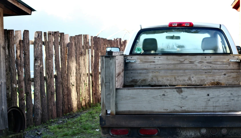 truck with flat bed and doors open in front of wood fence