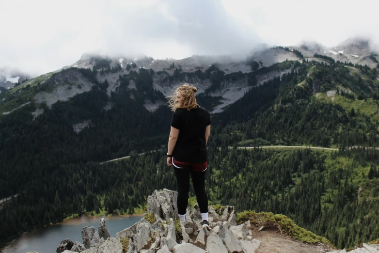 a person stands on a cliff overlooking mountains
