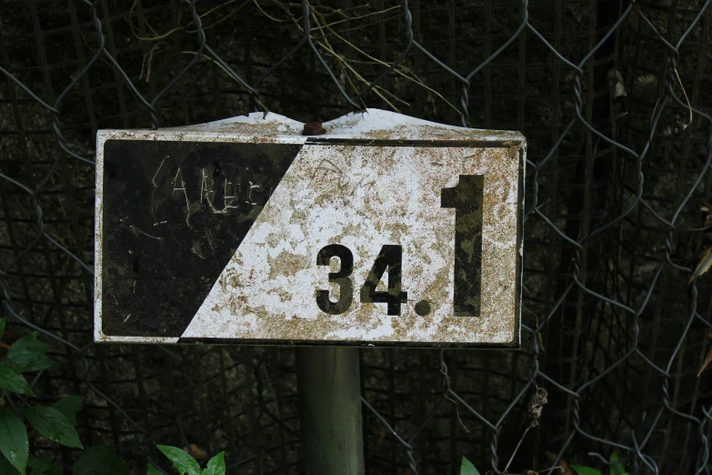 an old street sign placed in front of a metal fence