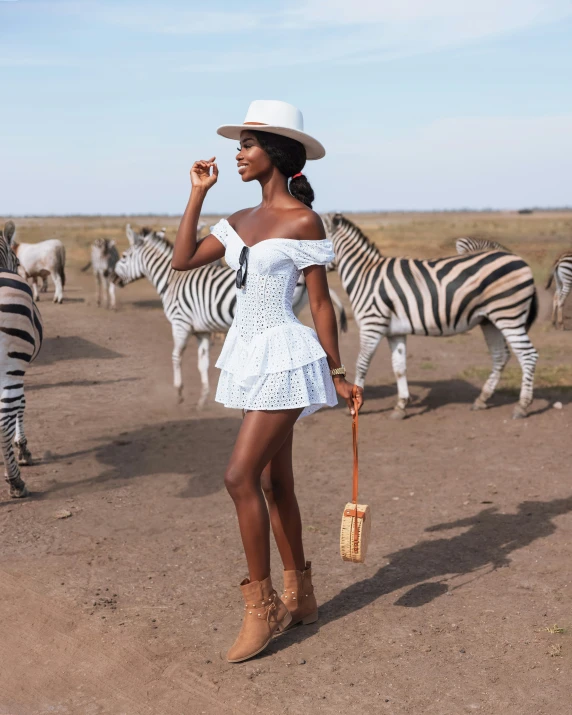 a woman in white dress and hat standing next to ze