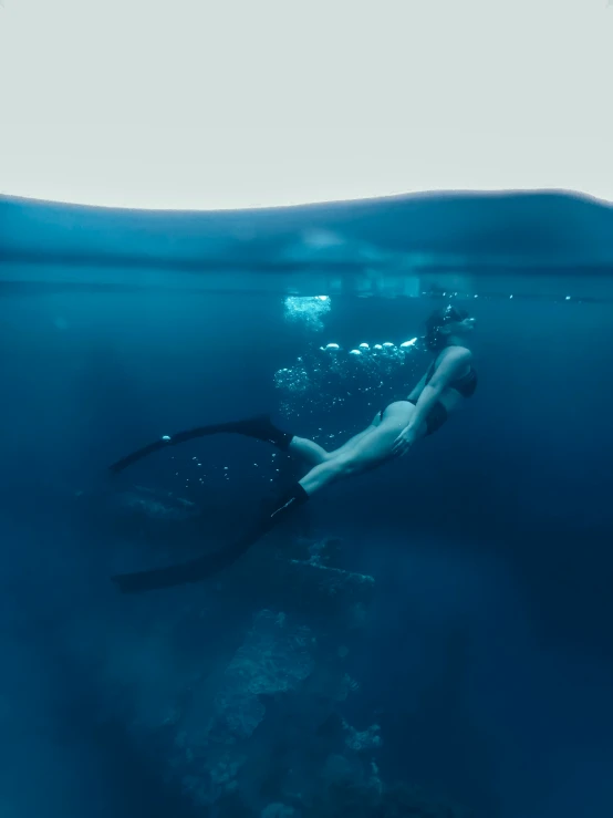 woman diving in the ocean with blue water