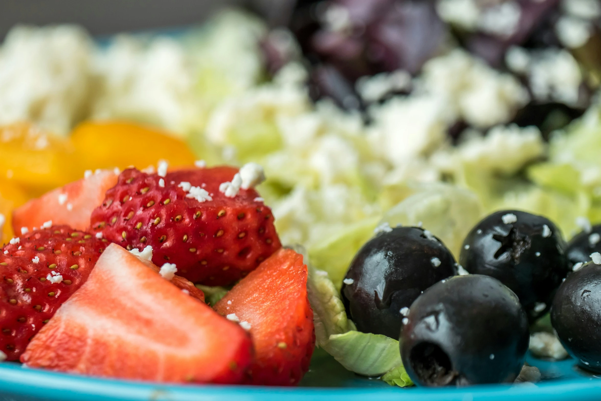 a blue plate with some strawberries and a salad