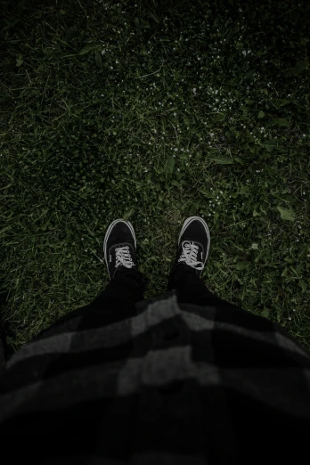 a person in black and white pants standing near grass