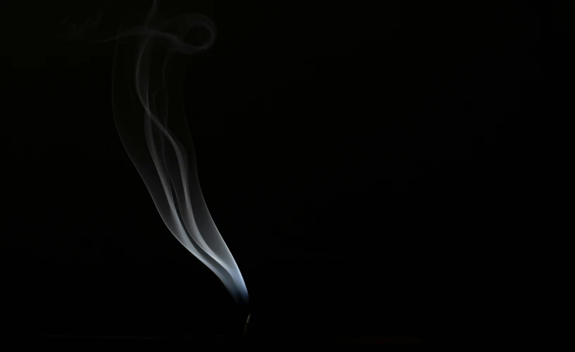 a white cigarette emitting steam on a black background