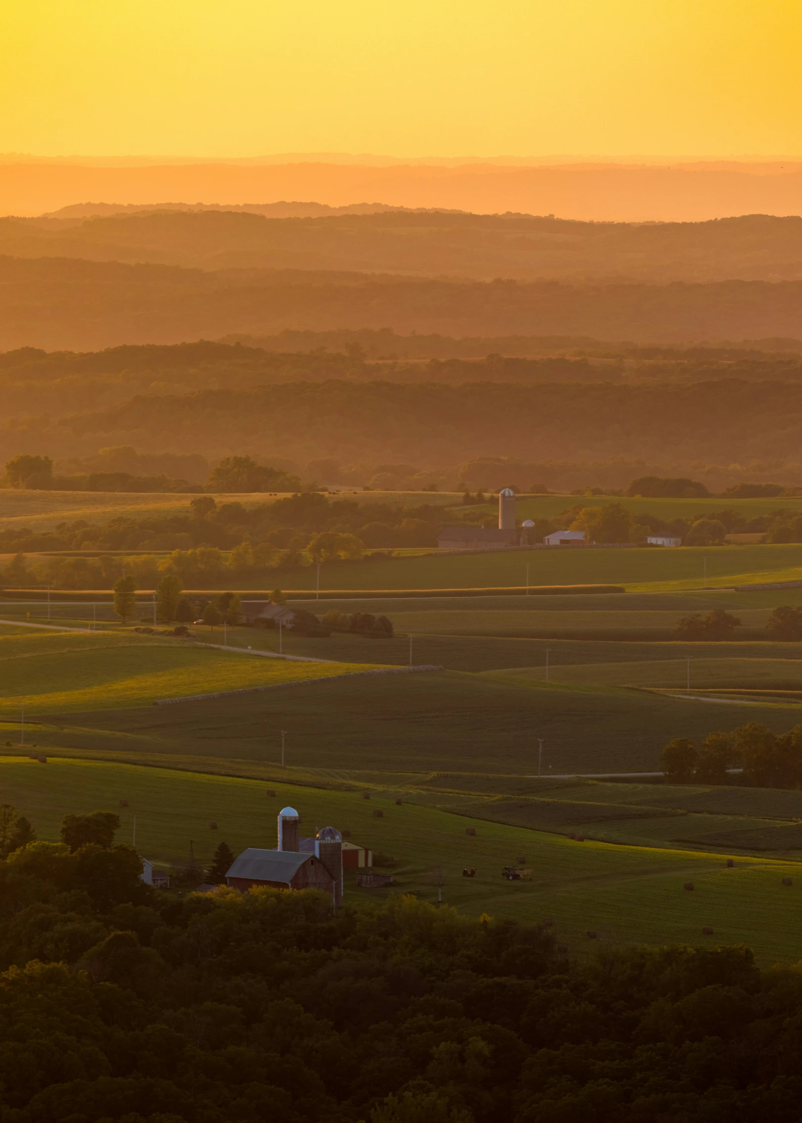 a rural valley at sunset with an airplane flying in the sky