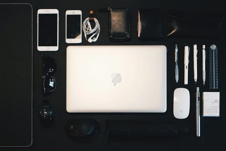 an open macbook, mouse, wallet and other office supplies on a desk