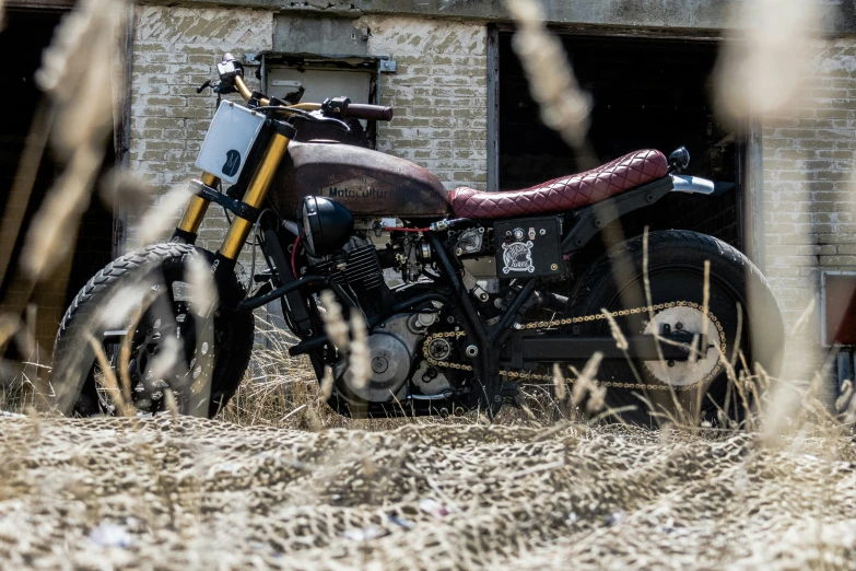 a motorcycle parked on dry grass in front of a building