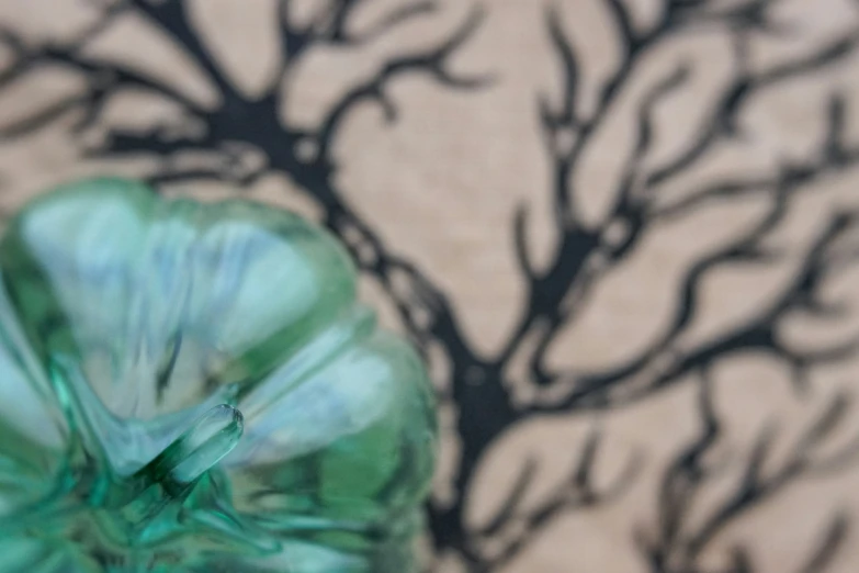 an artistic po of a green vase with trees casting shadows