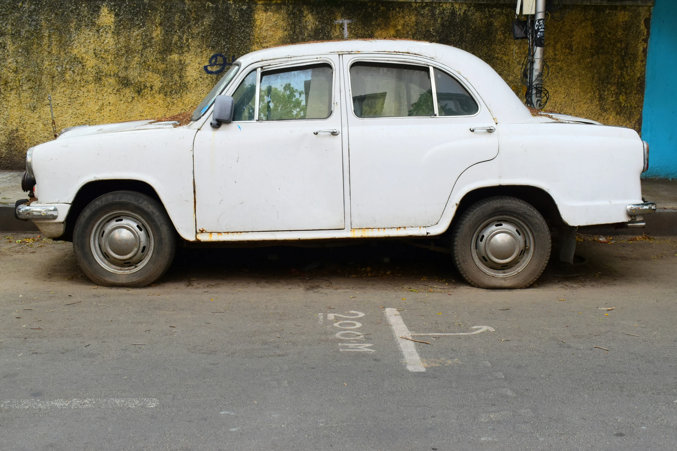 an old white car is parked on the side of the road