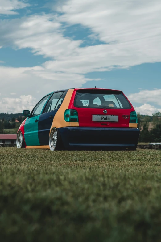 the back end of a colorful car parked in grass