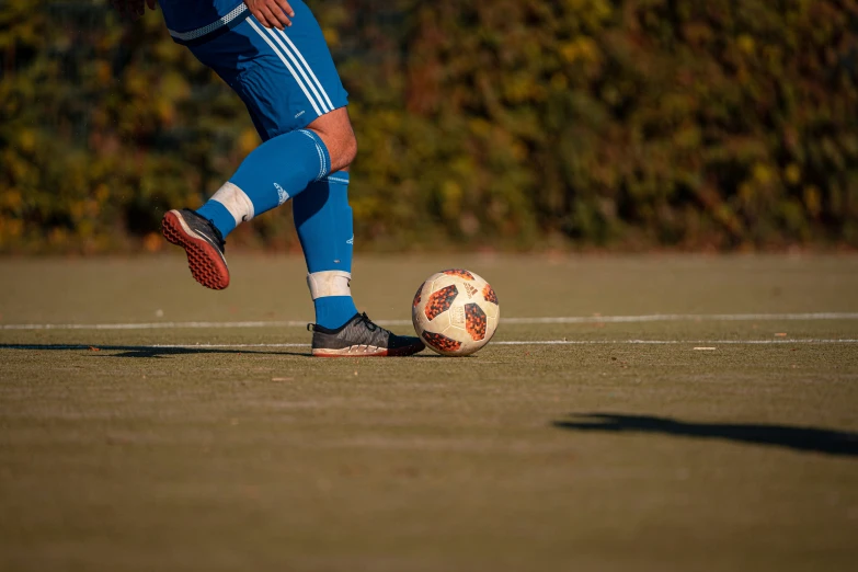 a soccer player is kicking the ball on the ground