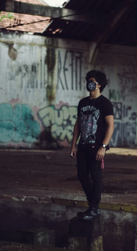 a man with a face mask on standing in front of graffiti wall