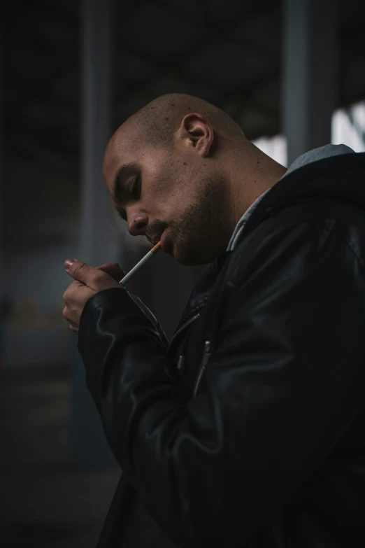 a man wearing a black leather jacket smoking a cigarette