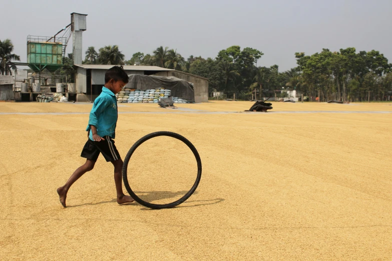 a boy is hing an oversized tire through the street