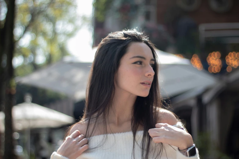 a woman in off the shoulder sweater standing in a town square