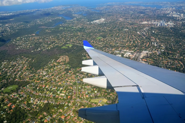 an airplane wing above a grassy area with trees