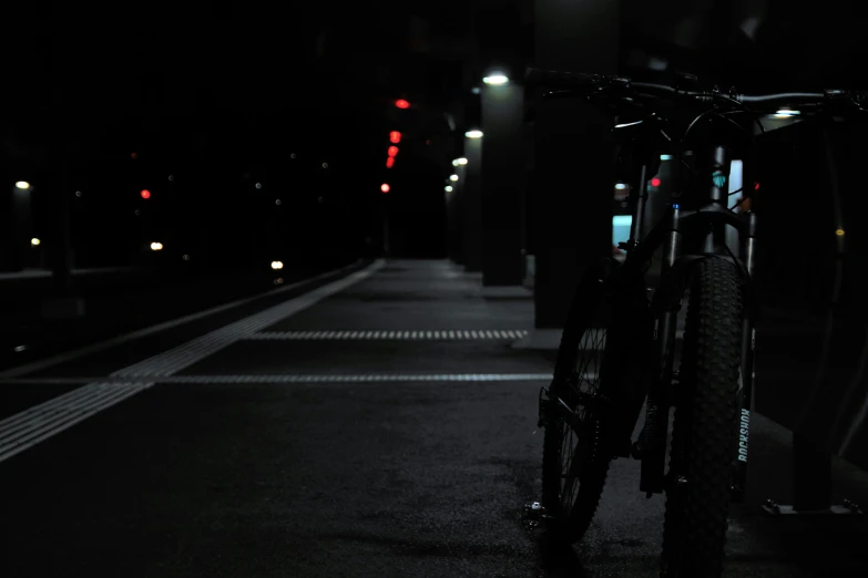 a bicycle leaning against the side of a street with lights shining at night