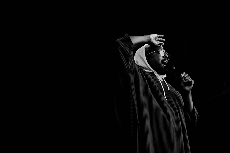 a man standing in the dark holding his hands up