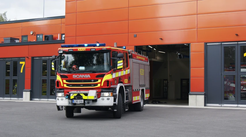 a large red fire truck in front of an orange building