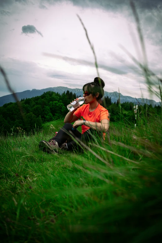 a woman sitting on top of a grass covered field