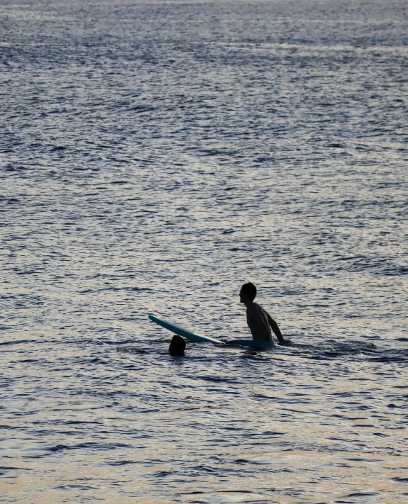 a man and his dog sit on their surfboards as they paddle through the ocean