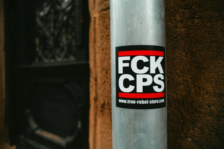 a grey sticker is seen on a pole in front of the building