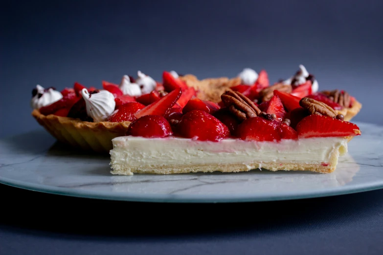 a dessert of cheesecake with red fruit and pecans