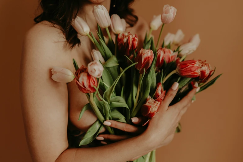 woman holding red and pink flowers on chest