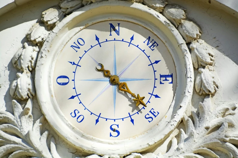 an elaborately decorated white clock with yellow numbers