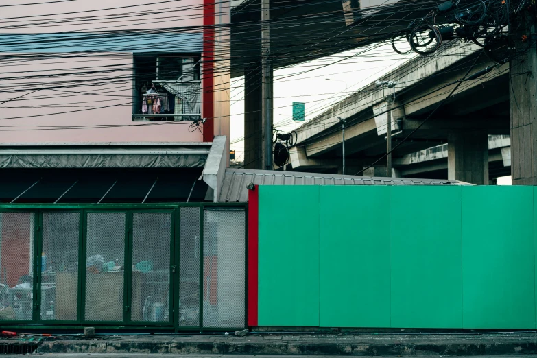 a green wall sitting beside a road with many electrical wires