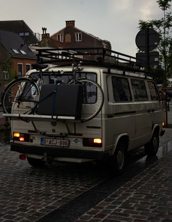 there is a van parked on the street with a bicycle on top