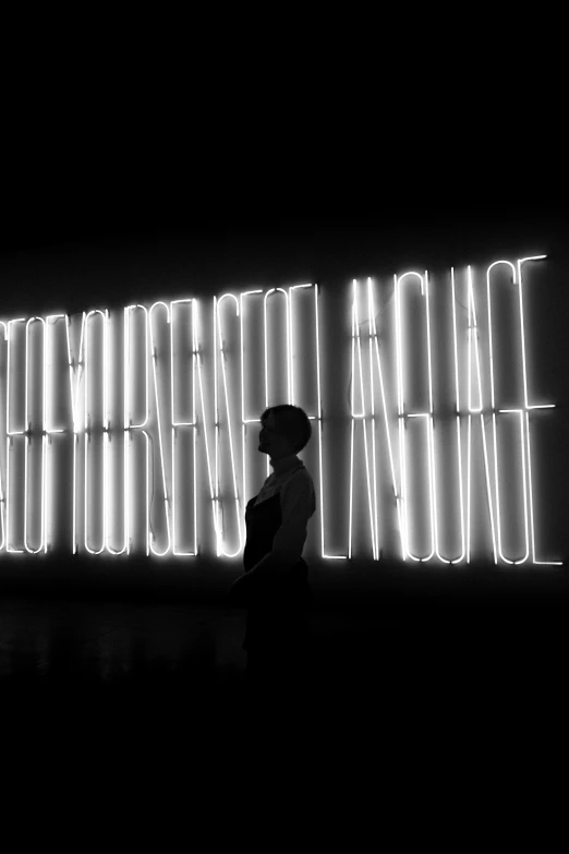 silhouetted person with umbrella, in front of illuminated sign reading'brightening language '