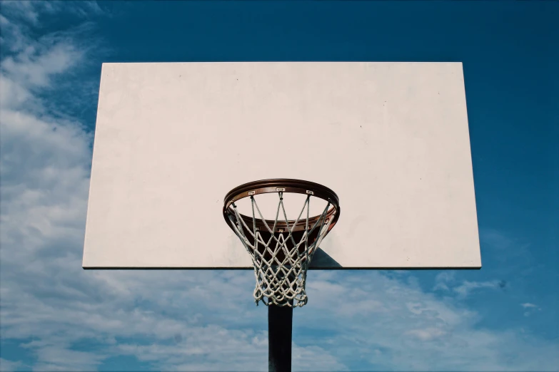 a basketball hoop and basket in mid air on a clear day