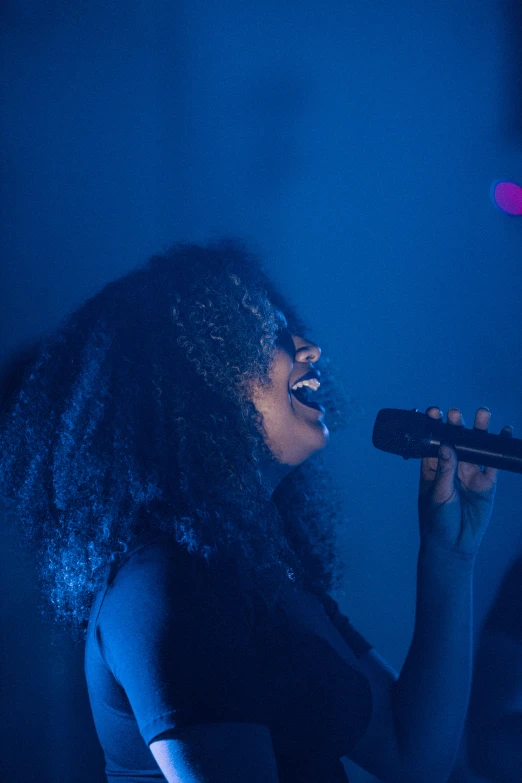 a woman in black dress singing into a microphone