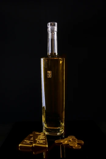 an empty bottle of alcohol on a black background next to a smaller bottle with gold numerals