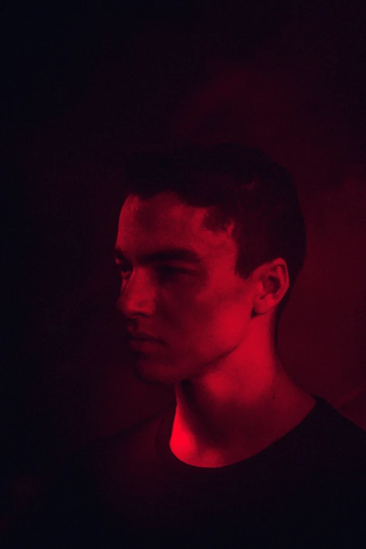 a man standing in a dark room with a red light shining on him