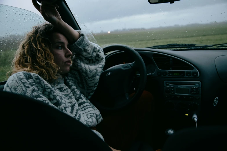 a woman driving in a car with a large umbrella