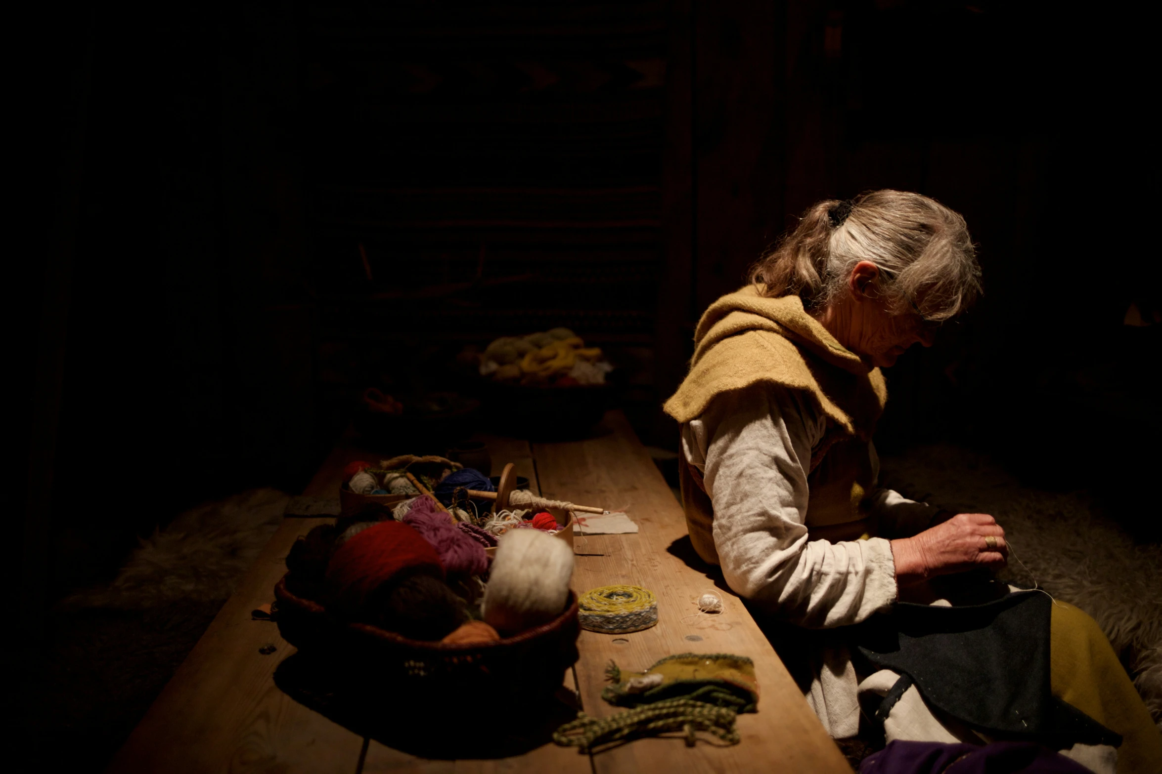 a person sitting on top of a wooden table in the dark