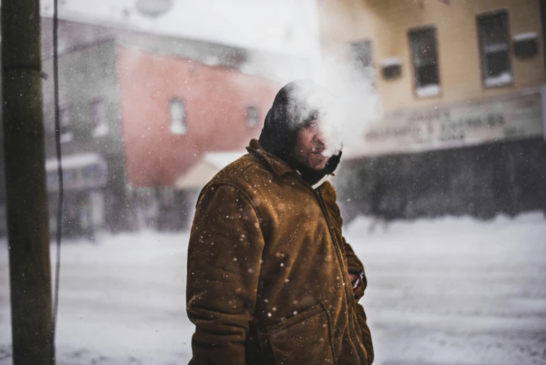 man standing alone in snow covered city with building behind him