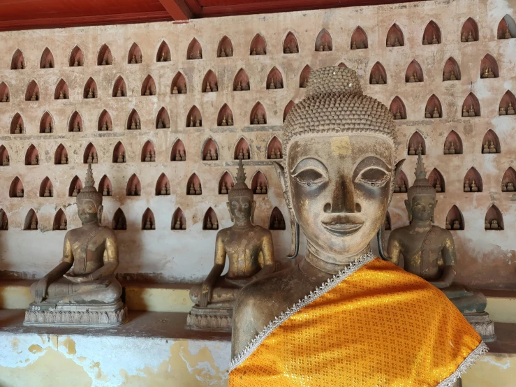 a gold towel covering a buddha statue in front of a wall