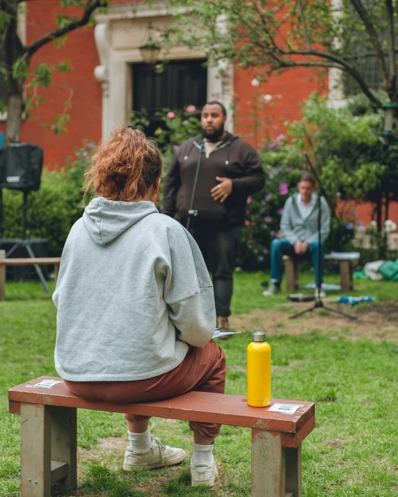 a man and woman sitting on a bench while another person stands behind