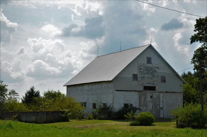 an old run down barn is shown in a field