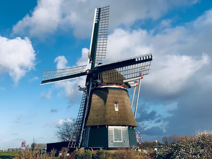 a tall wooden windmill sitting next to a green field