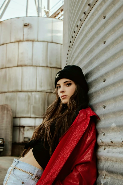 a woman in red jacket leaning on metal tank