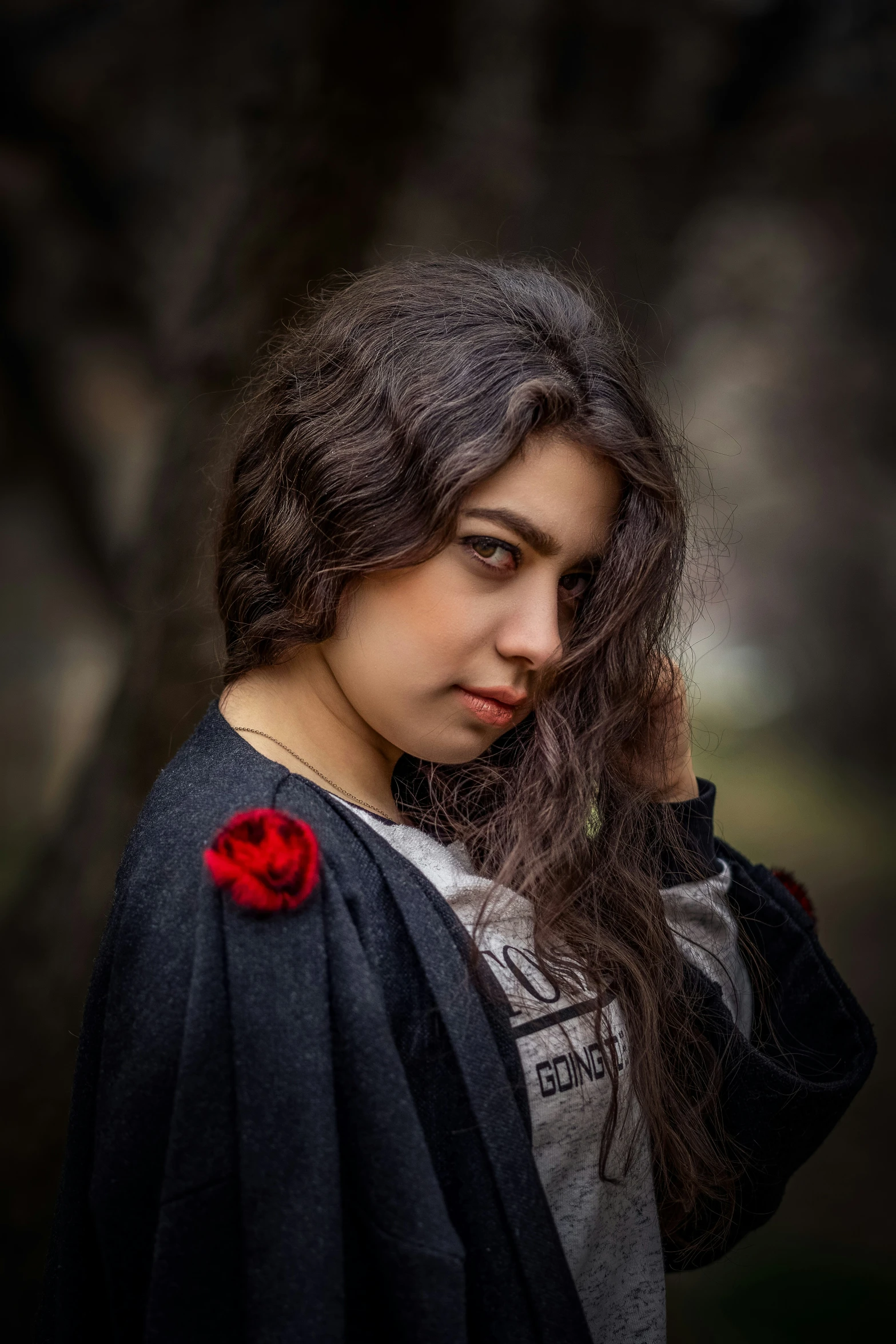 woman with rose in hand standing under tree