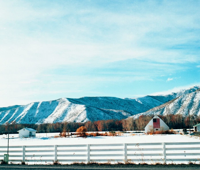 two white farm buildings in front of mountains