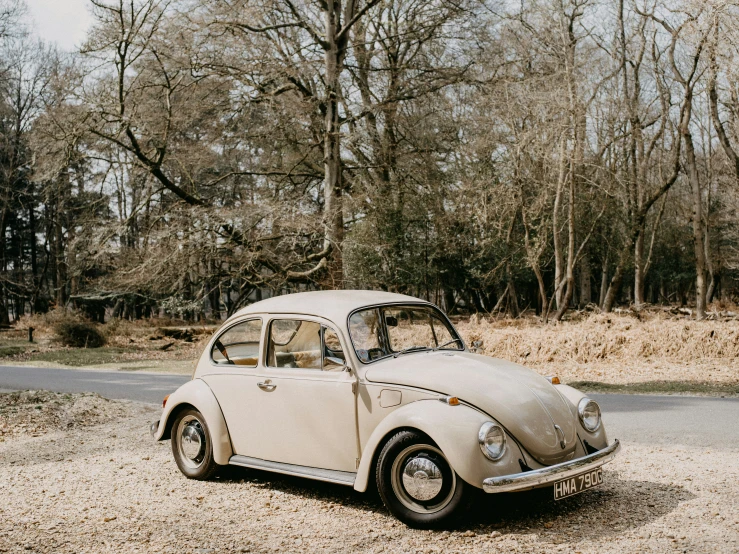 a classic car sits parked on some gravel