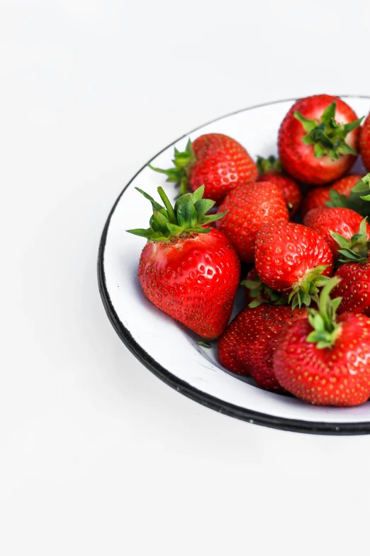 a bowl of fresh strawberries on top of a table