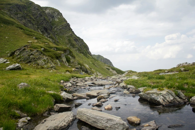 rocky river flowing through the center of a grassy valley